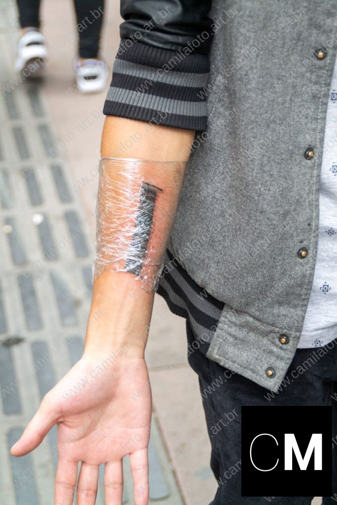 uma pessoa mostrando o antebraço e a tatuagem. 100 CNY é parte da série outras estórias por Ca Mila