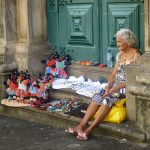 uma vendedora ambulante sentada ao lado dos seus produtos. américa é parte da série (pop)ulares por Ca Mila
