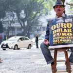 um promotor de vendas sentado em um banco de madeira. américa é parte da série (pop)ulares por Ca Mila