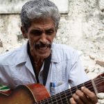 um artista de rua tocando violão. américa é parte da série (pop)ulares por Ca Mila