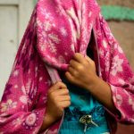 uma criança com blusa azul e com a face escondida pela jaqueta cor-de-rosa. 1,2,3 e... é parte da série emoções por Ca Mila