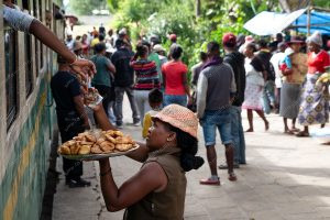 uma vendedora ambulante vendendo na estação de trem. 163 km é parte da série outras estórias por Ca Mila