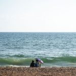 duas pessoas sentadas na praia. bem-querer é parte de emoções por Ca Mila.