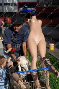 duas pessoas interagindo, um carrinho de supermercado, um manequim e alguns cachorros. vida de cachorro é parte de outras estórias por Ca Mila