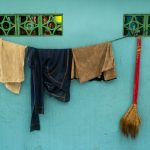 roupas penduradas num varal e uma vassoura. rua é parte de outras estórias por Ca Mila